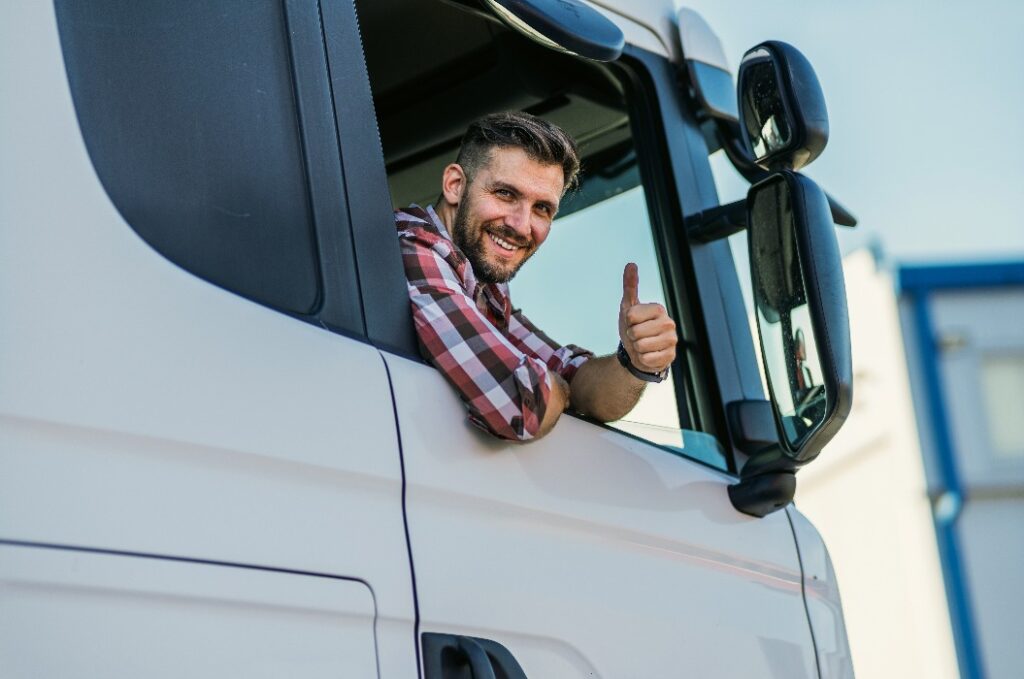 Truck driver sitting in his truck showing thumbs up. Trucker occupation. transportation services.